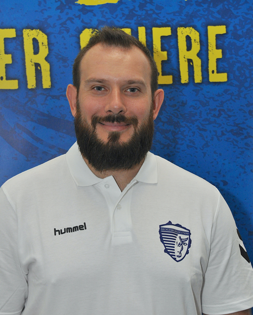 Mann in weißem Hemd mit Sportlogo vor einem blauen Hintergrund