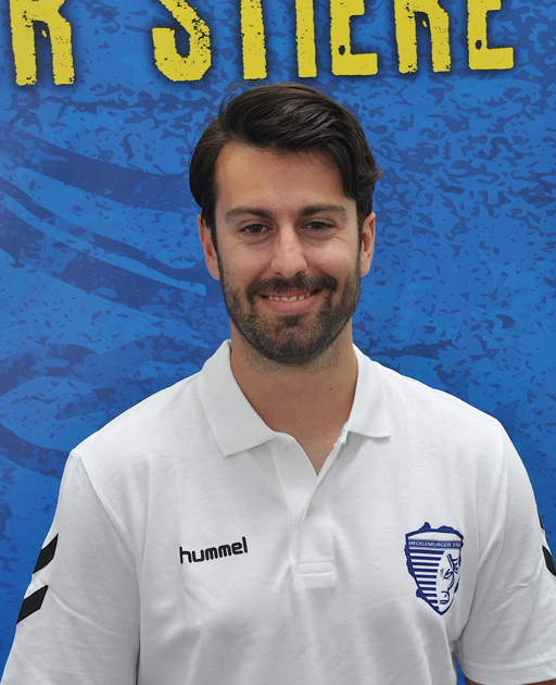 Person in weißem Hummel-Poloshirt vor blauem Hintergrund